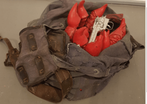 Kunstobjekt Rucksack mit roten Zwergen und Revolver